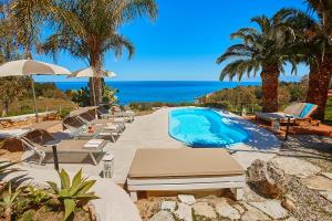 a swimming pool with lounge chairs and the ocean at Villa Gabbiano - Scopello-Villas in Scopello