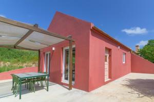 a red house with a green table on a patio at Cozy Countryside Studio in Aldeia do Cano