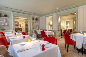 a restaurant with white tables and red chairs at Hotel Westminster in Paris