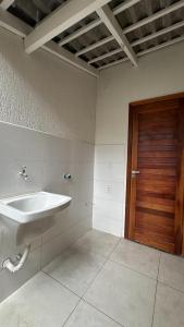 a bathroom with a sink and a wooden door at Casa nova, confortável e funcional em Redação-PA in Redenção