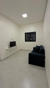 a living room with a black couch and a tv at Casa nova, confortável e funcional em Redação-PA in Redenção