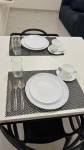 a table with white plates and silverware on it at Casa nova, confortável e funcional em Redação-PA in Redenção