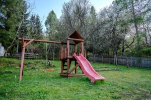 a wooden playground with a slide in a yard at Kiskörtés Vendégház Óhuta in Háromhuta