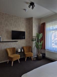 a hotel room with two chairs and a television at Boutique Hotel De Raetskamer in Noordwijkerhout
