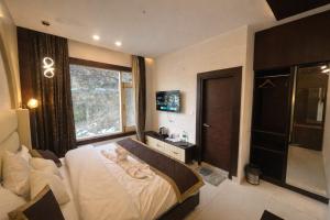a bedroom with a large bed and a window at Hotel Shaurrat in Shimla +24 photos