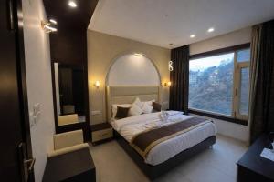 a bedroom with a large bed and a large window at Hotel Shaurrat in Shimla