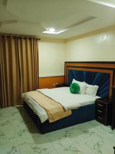 a bedroom with a large bed with a blue headboard at OUR HILLs HOTELs AND SUITES in Ekoro +21 photos