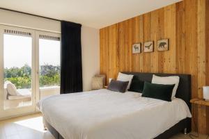 a bedroom with a large bed and a large window at Het Kastanjehuis in Orlitain