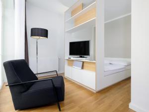 a living room with a black chair and a television at smartments Hamburg Aussenalster in Hamburg
