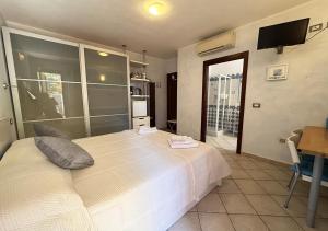 a bedroom with a large white bed and a kitchen at Crisalide in La Maddalena