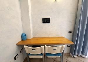 a wooden table with two white chairs and a table at Crisalide in La Maddalena +20 photos