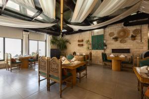 a dining room with tables and chairs and windows at Dolphin Continental Hotel in Kuwait