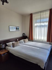 a bedroom with a large bed with a large window at Boutique Hotel De Raetskamer in Noordwijkerhout