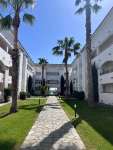 a walkway in front of a building with palm trees at APPARTEMENT sognu di rena G1 in San-Nicolao