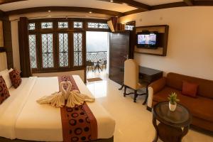 a bedroom with a bed and a couch and a television at Hotel Morning Lake in Nainital +30 photos