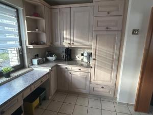 a white kitchen with white cabinets and a window at Ferienhaus Windrödel in Herzhausen