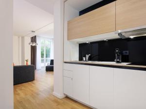 a kitchen with white cabinets and a living room at smartments Hamburg Aussenalster in Hamburg