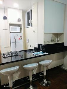 a kitchen with two white stools and a counter at Village Copacabana in Rio de Janeiro