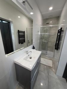 a white bathroom with a sink and a shower at Apartament Centrum Chojniczanka in Chojnice