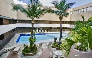 a swimming pool with palm trees in a building at Duplex Close to HPU Waikiki Pool Terrace Laundry One and Half Bath for 15person in Honolulu