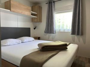 a bedroom with a bed with two pillows and a window at Camping de Contrexeville in Contrexéville