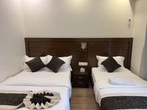 two beds in a hotel room with white sheets and pillows at The Kagbeni Hotel in Pokhara
