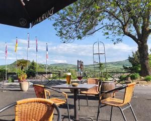 a table with chairs and a glass of wine on it at Hotel De Plein Air Le Chanset in Ceyrat