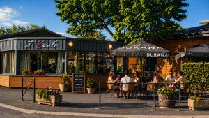 a group of people sitting at tables outside a restaurant at Hotel De Plein Air Le Chanset in Ceyrat