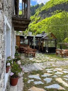 a patio with tables and benches and a building at Guesthouse Kujtimi in Theth