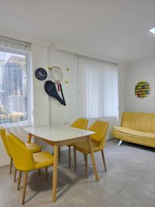a dining room with a table and yellow chairs at Smash Hostel Batumi in Batumi