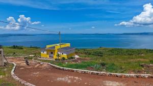 a yellow house on a hill next to the water at Marakunda - Victoria in Jinja +2 photos