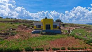 a yellow house on a hill in a field at Marakunda - Victoria in Jinja