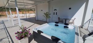 a hot tub on a patio with chairs and flowers at Cozy White House - Near Beach Private Jacuzzi in Ksamil