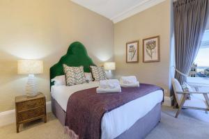 a bedroom with a bed with a green headboard at 20 Golf Place in St. Andrews