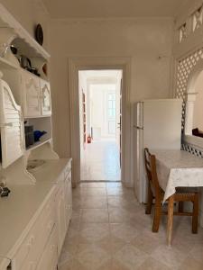 a white kitchen with a table and a refrigerator at Ágnes Nyaralóház in Siófok +13 photos