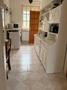 a kitchen with white cabinets and a tile floor at Ágnes Nyaralóház in Siófok