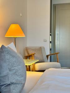 a room with a bed and a chair and a lamp at Plaza Rooms & Studios in Forchheim +2 photos