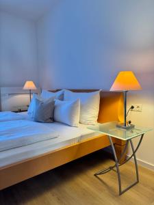 a bed with a table with a lamp on it at Plaza Rooms & Studios in Forchheim