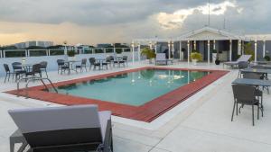 a pool on the roof of a building with tables and chairs at Microtel by Wyndham UP Technohub in Manila