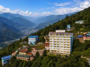 a hotel on a hill with mountains in the background at Pride Premier Darjeeling in Darjeeling