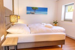 a bed with white sheets in a room at Lago Edera - Talblick in Hemfurth-Edersee