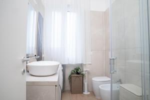 a white bathroom with a sink and a toilet at The Castle Apartment in Brescia