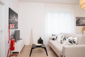 a white living room with a couch and a table at The Castle Apartment in Brescia