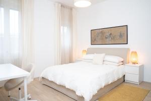 a white bedroom with a white bed and a desk at The Castle Apartment in Brescia