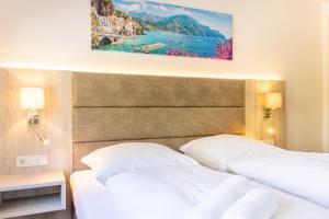 two beds in a hotel room with a painting on the wall at Lago Edera - Panoramablick in Hemfurth-Edersee