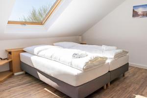 a bedroom with a bed with white sheets and a window at Lago Edera - Seeblick in Hemfurth-Edersee
