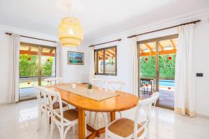 a dining room with a wooden table and white chairs at Llenaire Gran Beach House in El Port