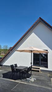 a table and chairs with an umbrella in a parking lot at Ferienwohnung Melle - Westerhausen in Melle