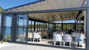 a dining area with tables and chairs and windows at Apartments with sea view in Kožino