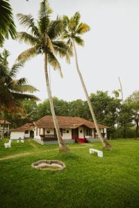 two palm trees in front of a house at Alleppey Backwater Resort in Alleppey
